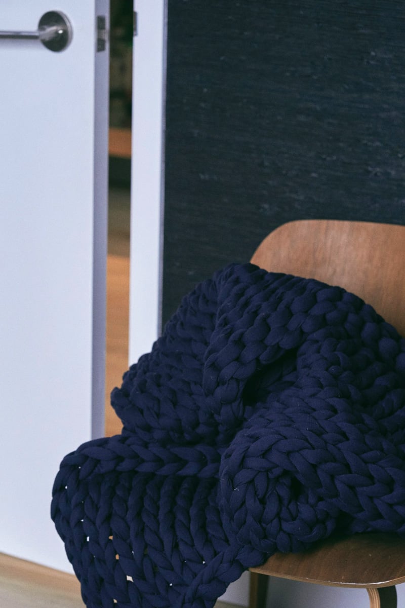 navy blanket on wooden chair